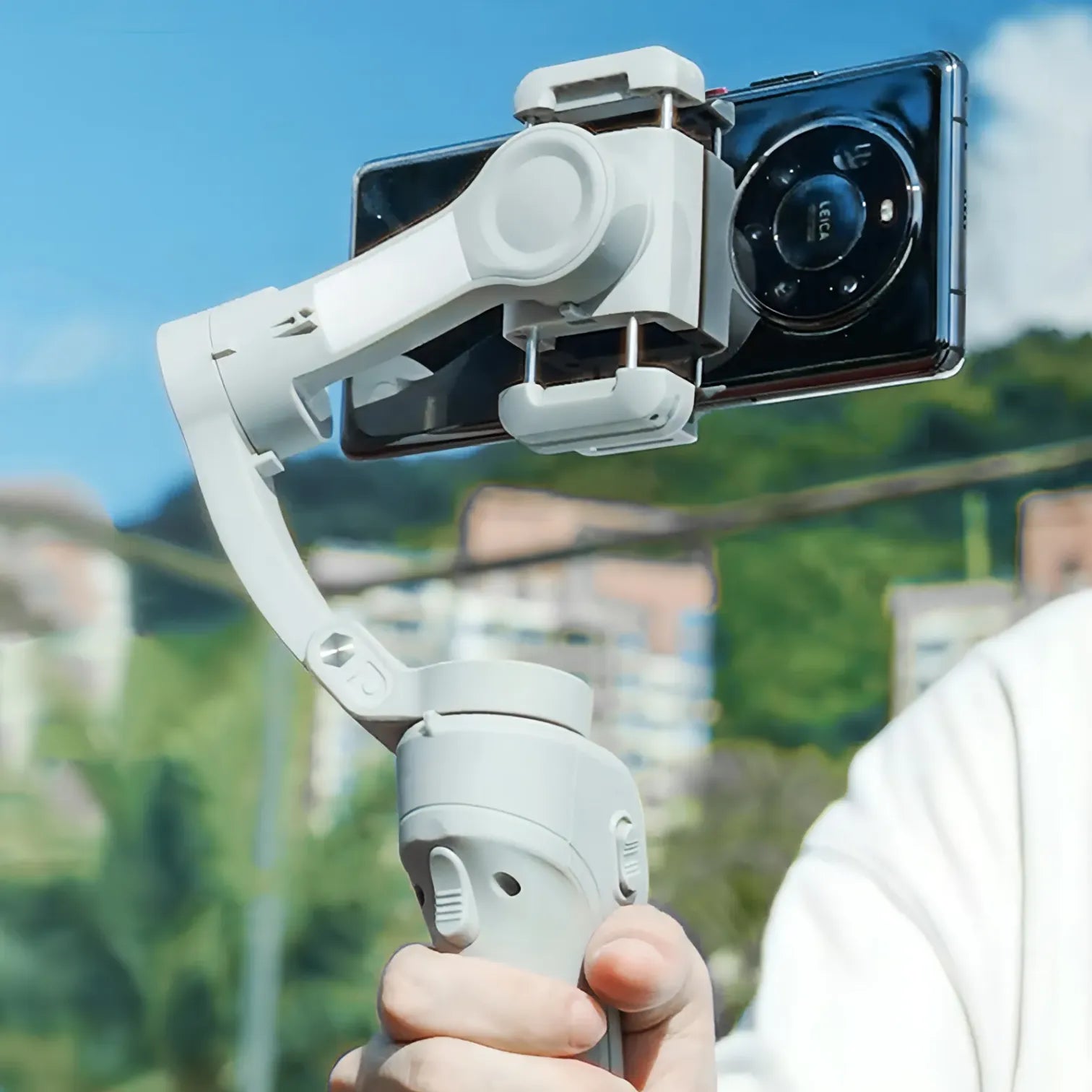 Hand holding a smartphone Bytech Gimbal with a clear sky and blurred background