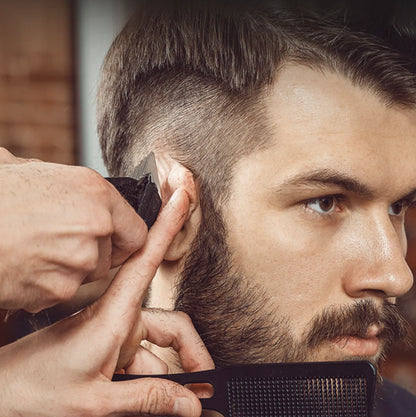 Barber trimming a customer's beard with a comb and Bytech Hair Clipper in a close-up shot.