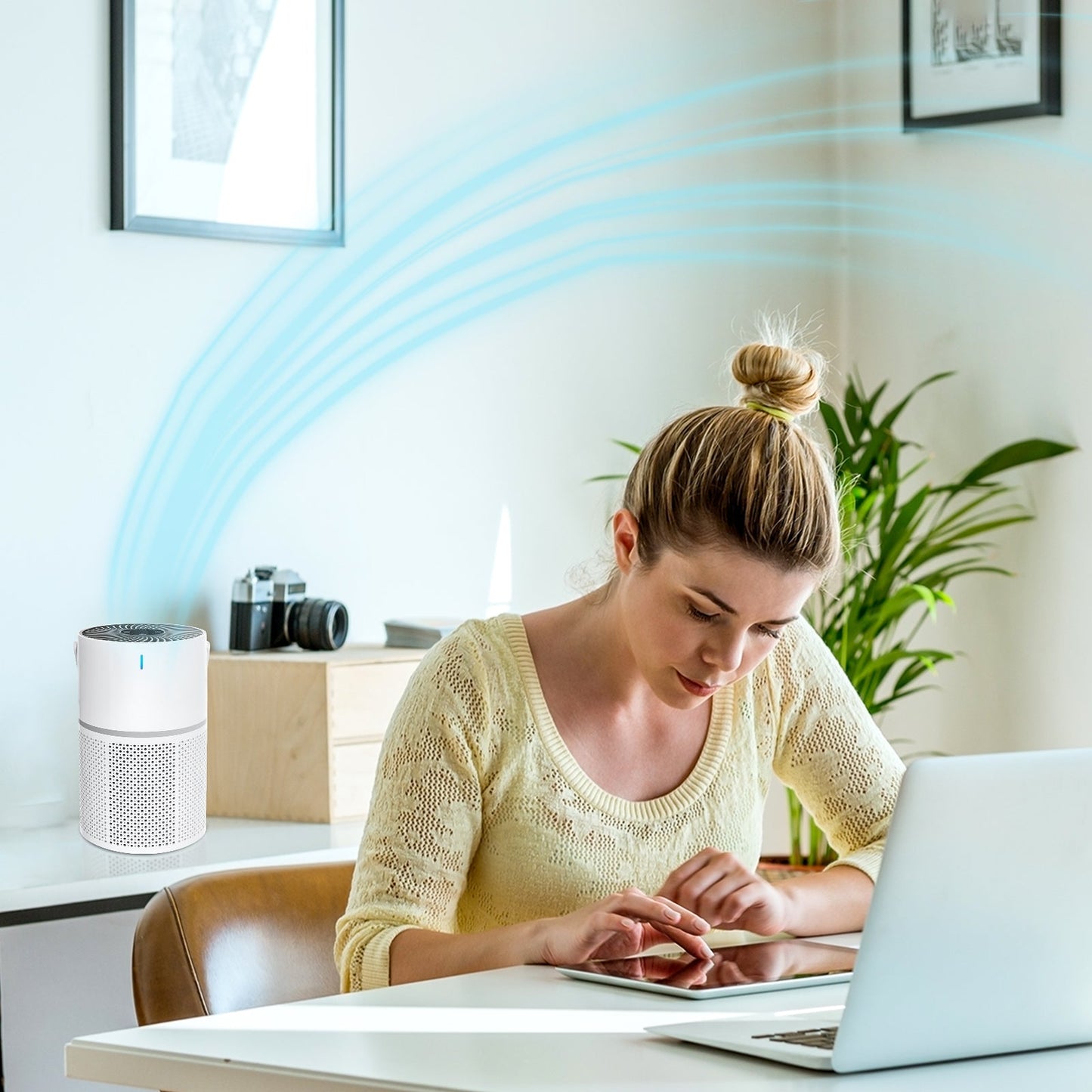 Woman using a laptop with an Klarity Air Purifier in the background