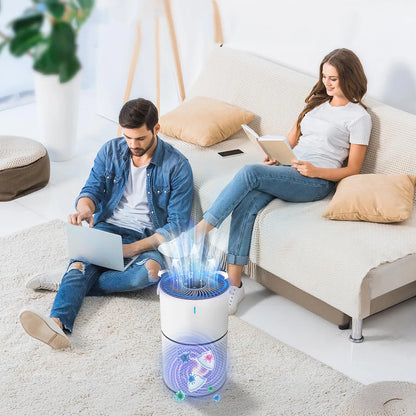 A cylindrical Sekoda Air Purifier with glowing blue airflow graphics is shown on a light rug in a bright living room, with a man using a laptop on the floor and a woman sitting on a sofa reading in the background.