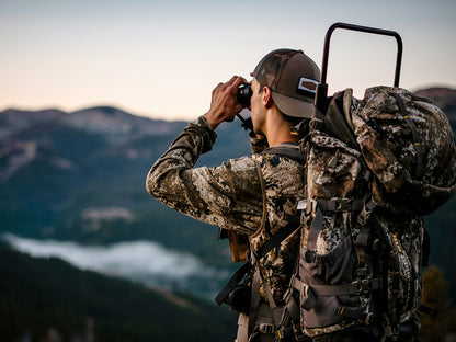 Person in camouflage gear using Bosco Apex HD-X1 Binoculars with mountains in the background
