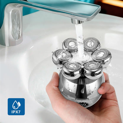 Hand holding a Vassco shaver head under running water from a faucet with an IPX7 logo.